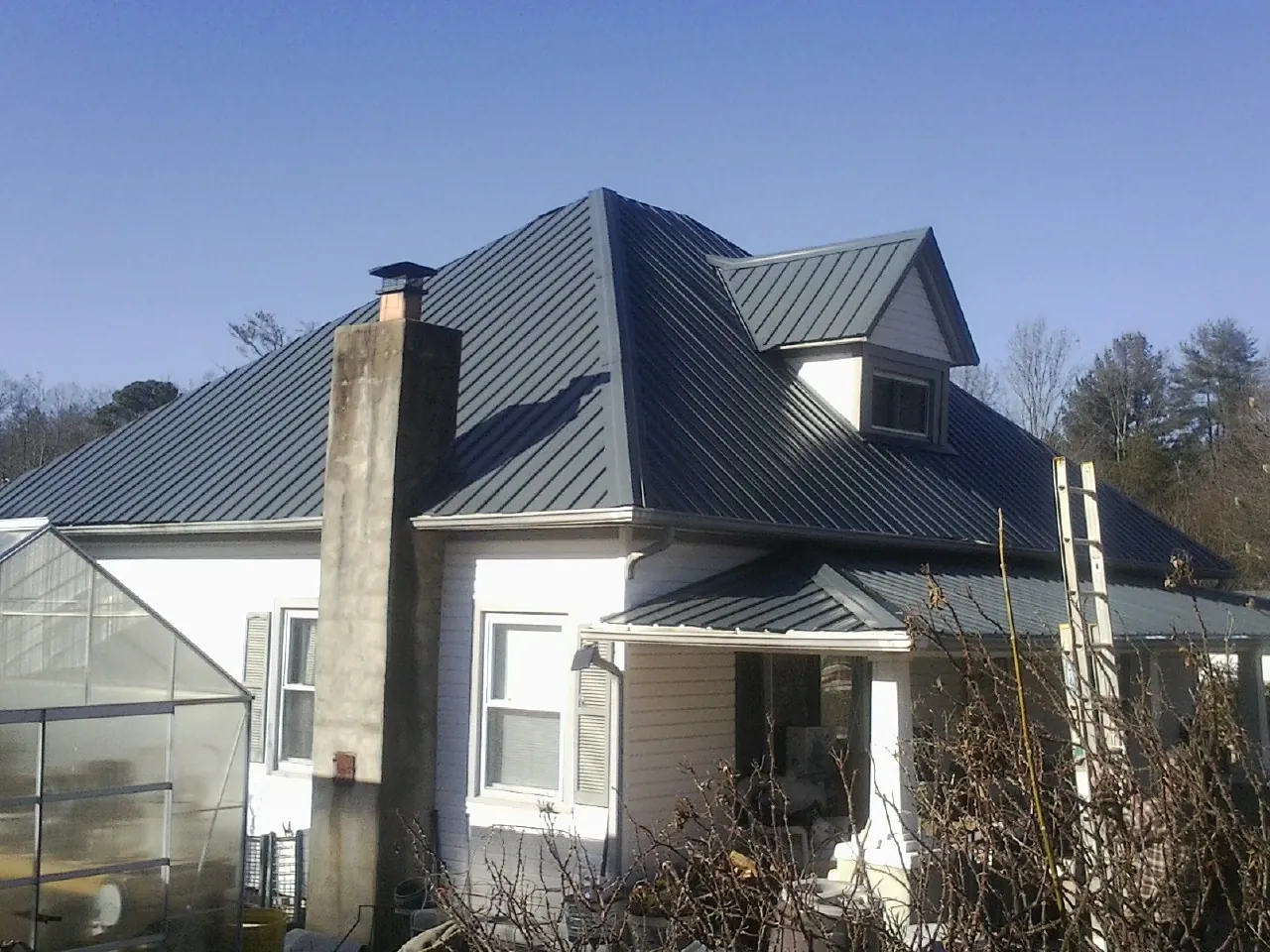 Dark blue standing seam metal roof on a white farmhouse with dormer — Slate & Tile Roof Repair by Roofing Brothers in Ferndale