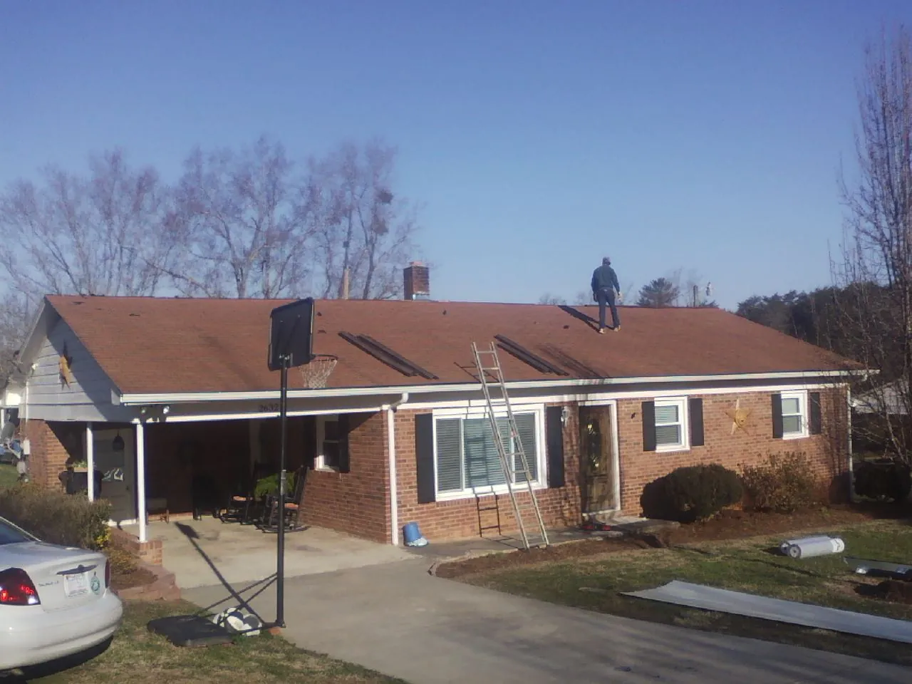 Roofer stripping a shingle roof on a brick ranch before metal panels in Ferndale